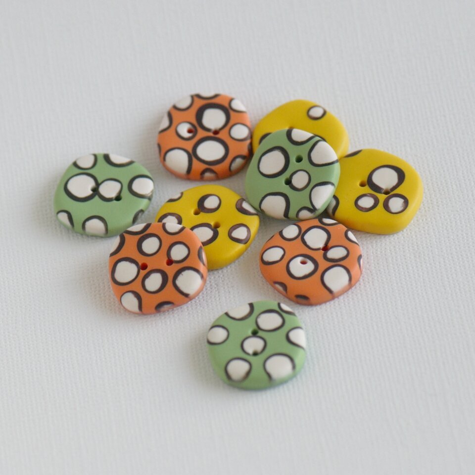 21 mm – 9 vnt. netaisyklingos apvalaino keturkampio formos oranžinės, žalios ir geltonos sagos su žaismingais rutuliukais